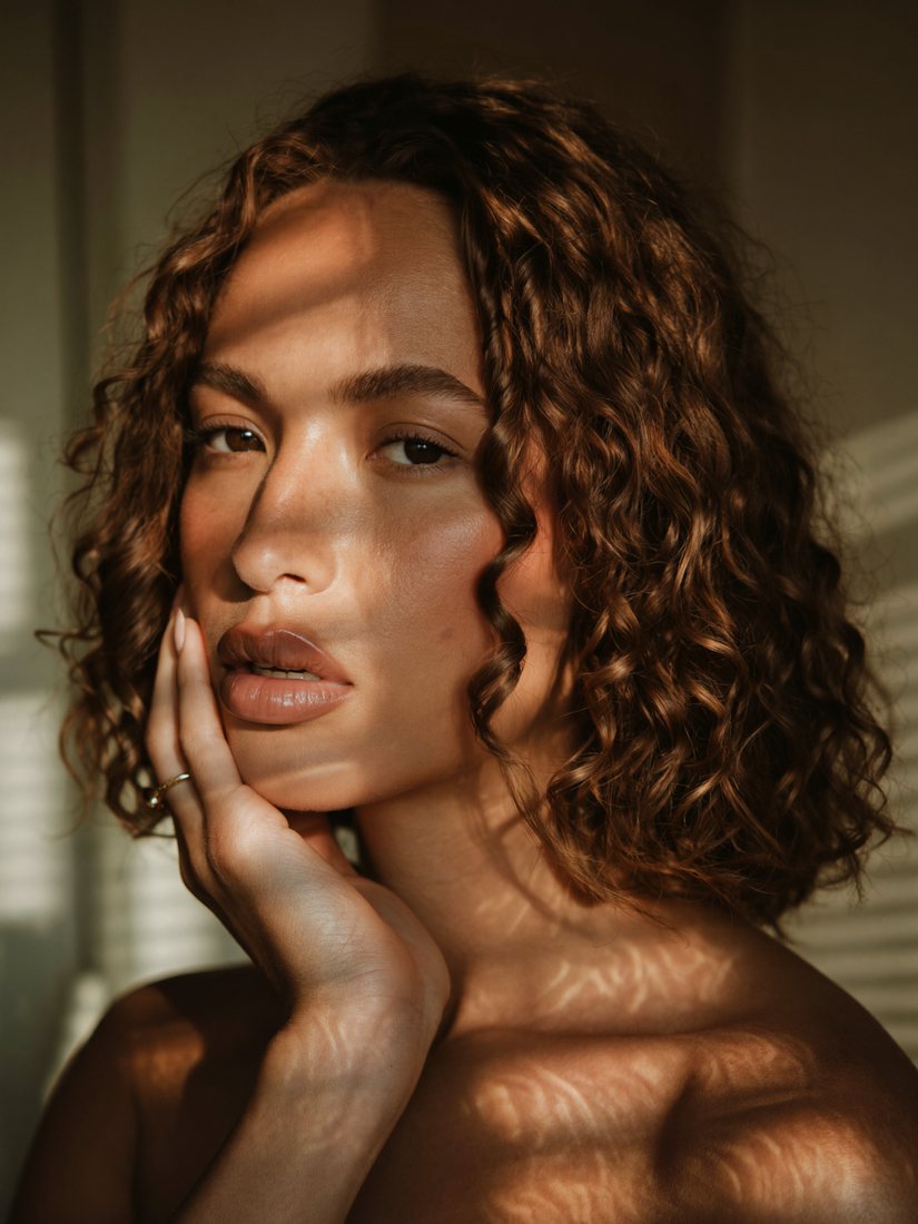Result: woman with hand on cheek in striped window light, now with curly shoulder-length brown hair