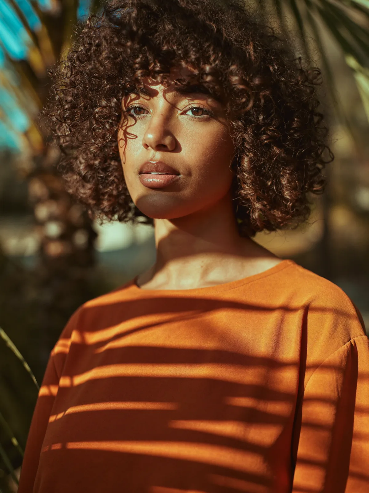Before: woman in an orange striped sweater with palm shadows